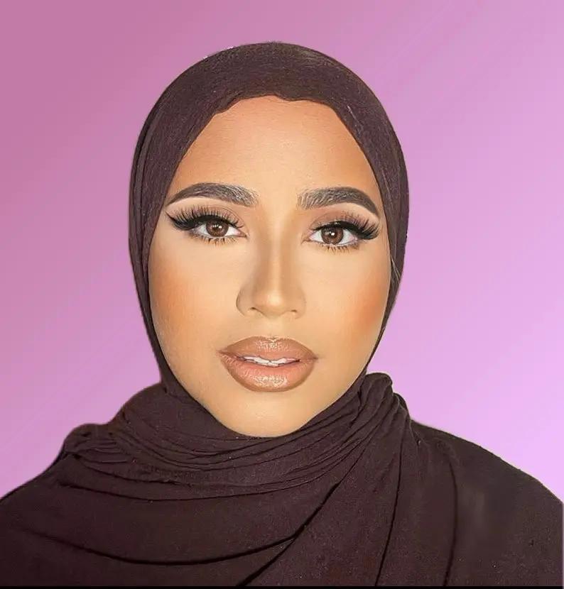 Person wearing a brown hijab against a pink background