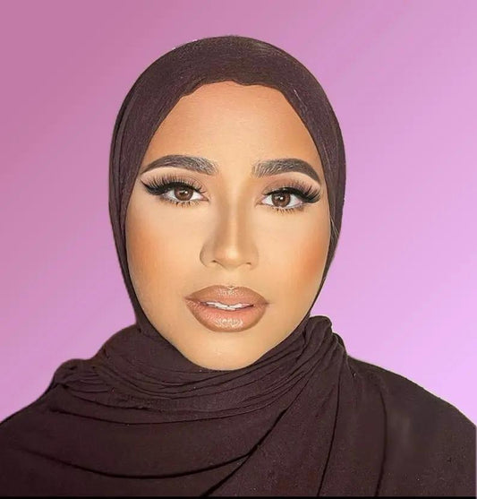 Person wearing a brown hijab against a pink background