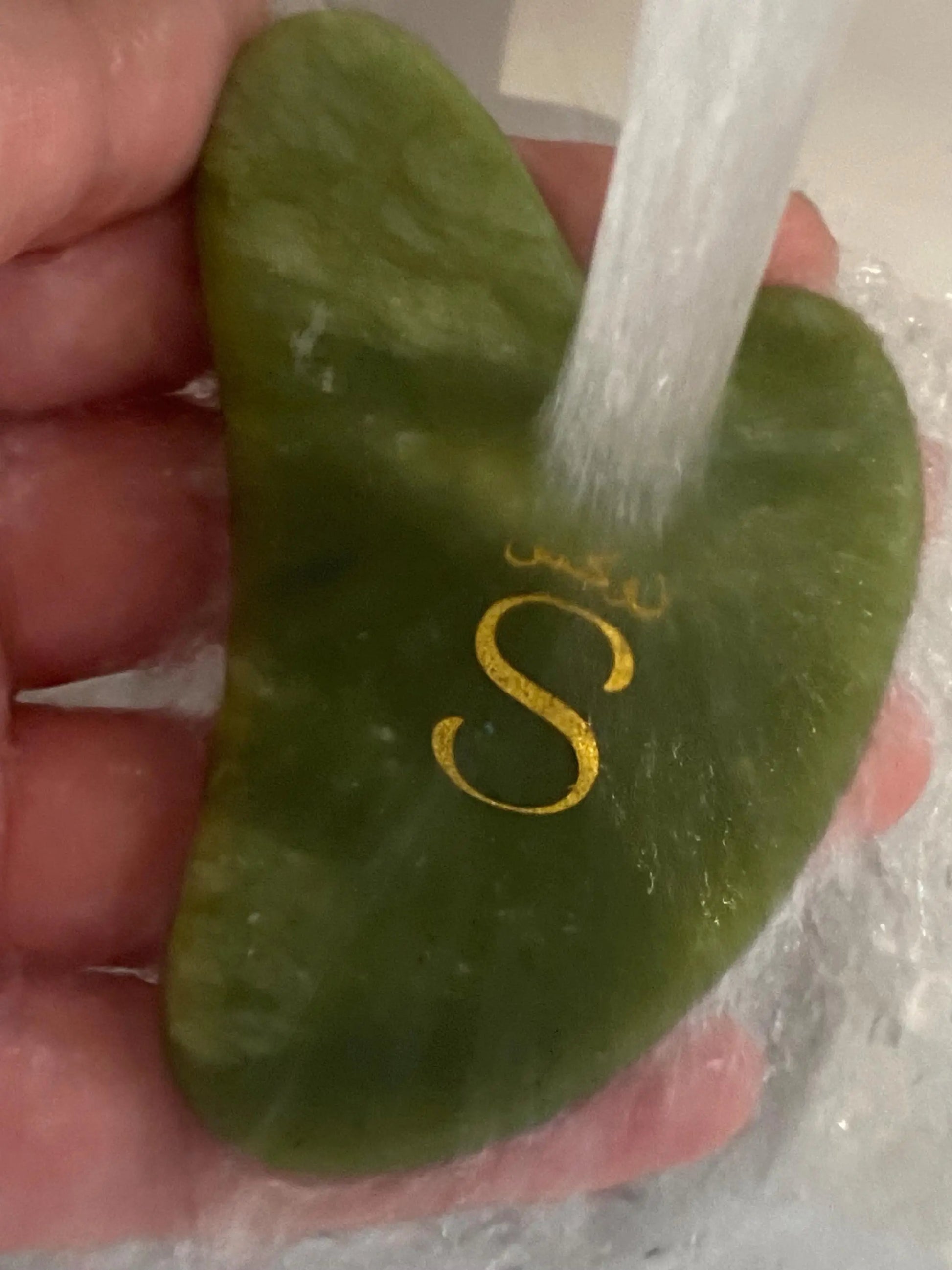 Close-up of a natural jade gua sha facial massage tool used for skincare routines