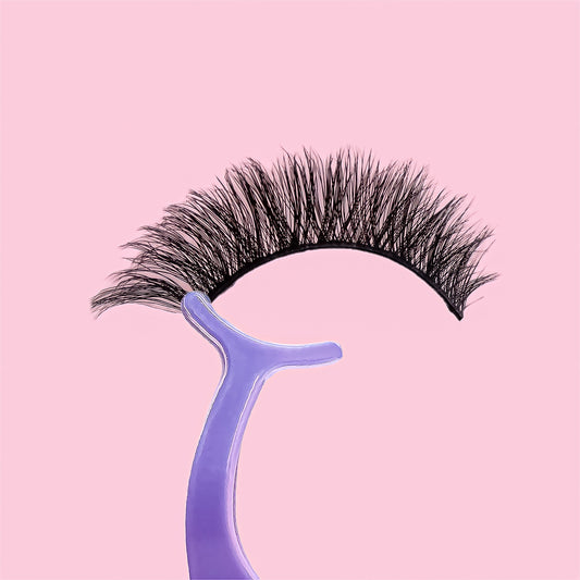 False eyelashes on a purple holder against a pink background