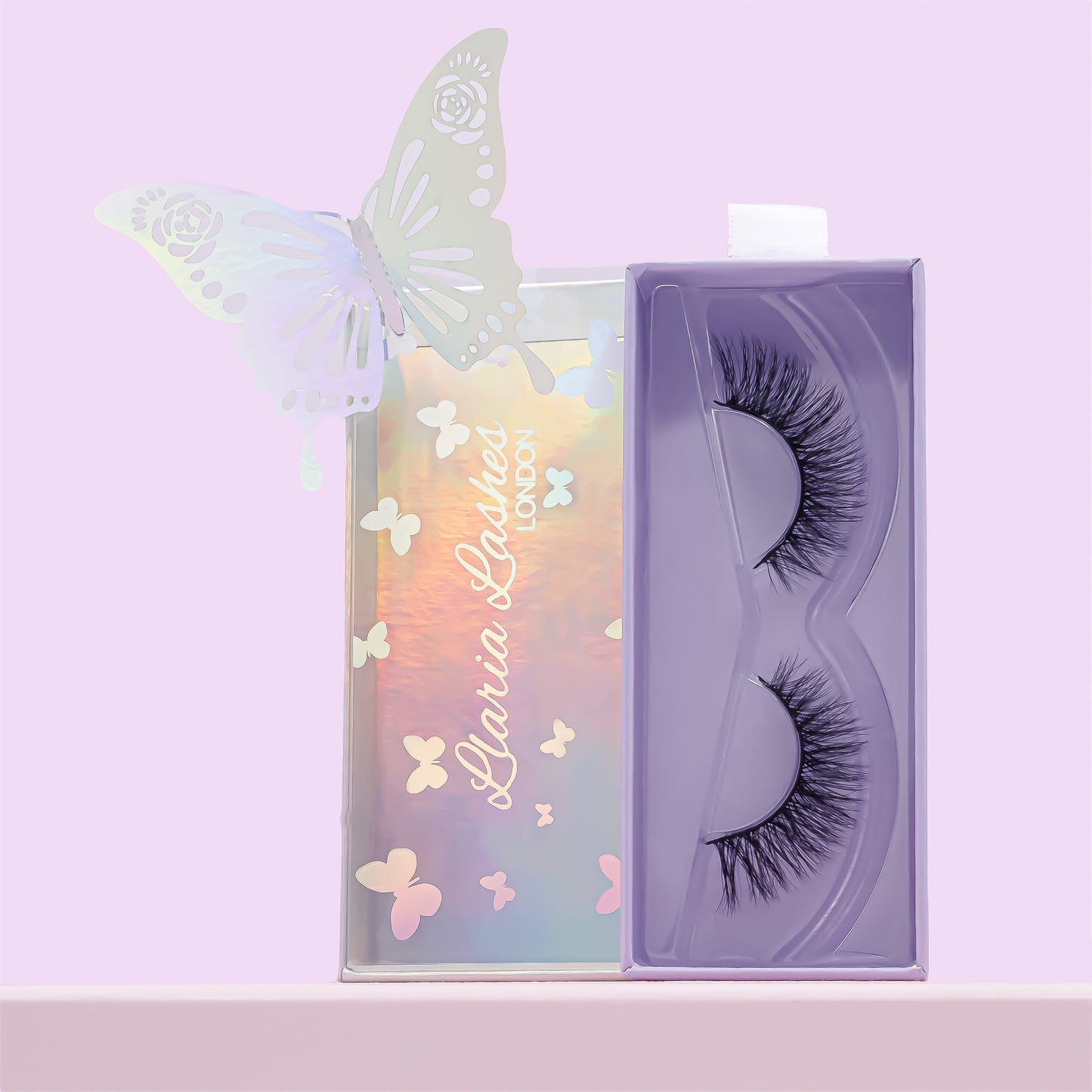 False eyelashes in a decorative box with butterfly designs on a light purple background