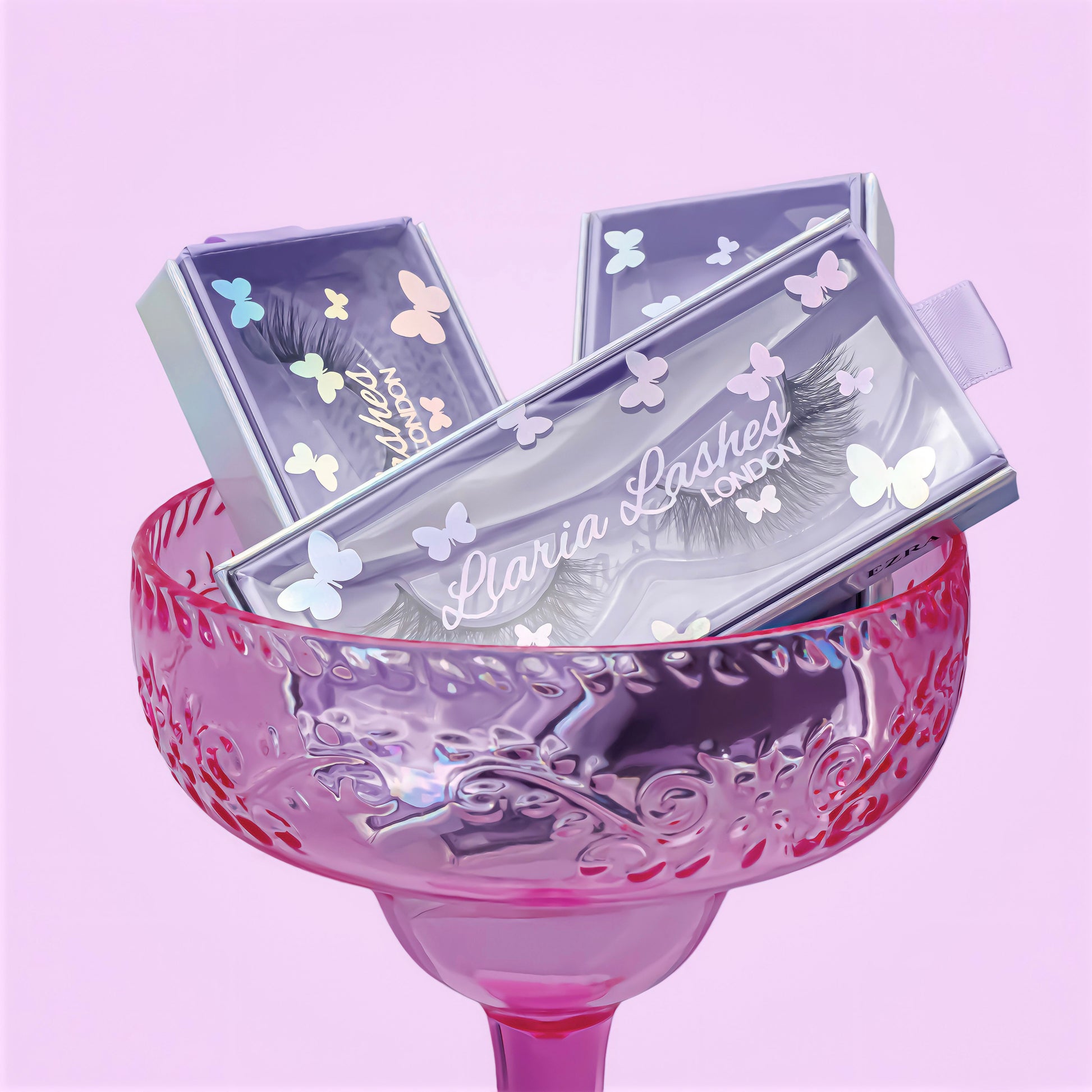 Eyelash packaging with butterfly designs on a pink glass against a light purple background