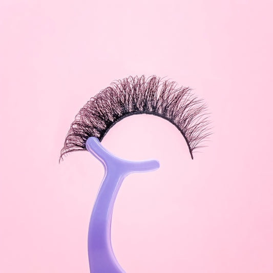 False eyelashes on a blue holder against a pink background