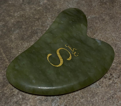 Green stone tool with gold 'S' logo on a brown surface