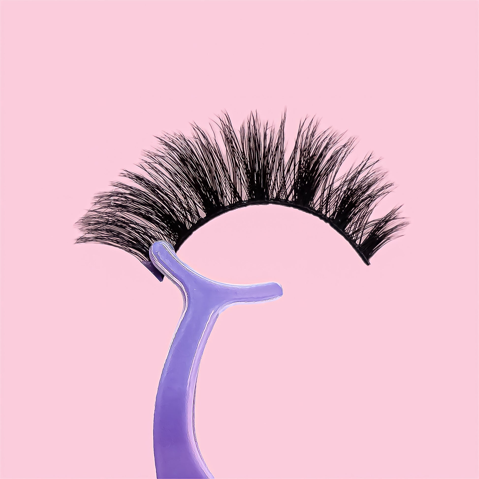 Pair of false eyelashes with a purple holder on a pink background