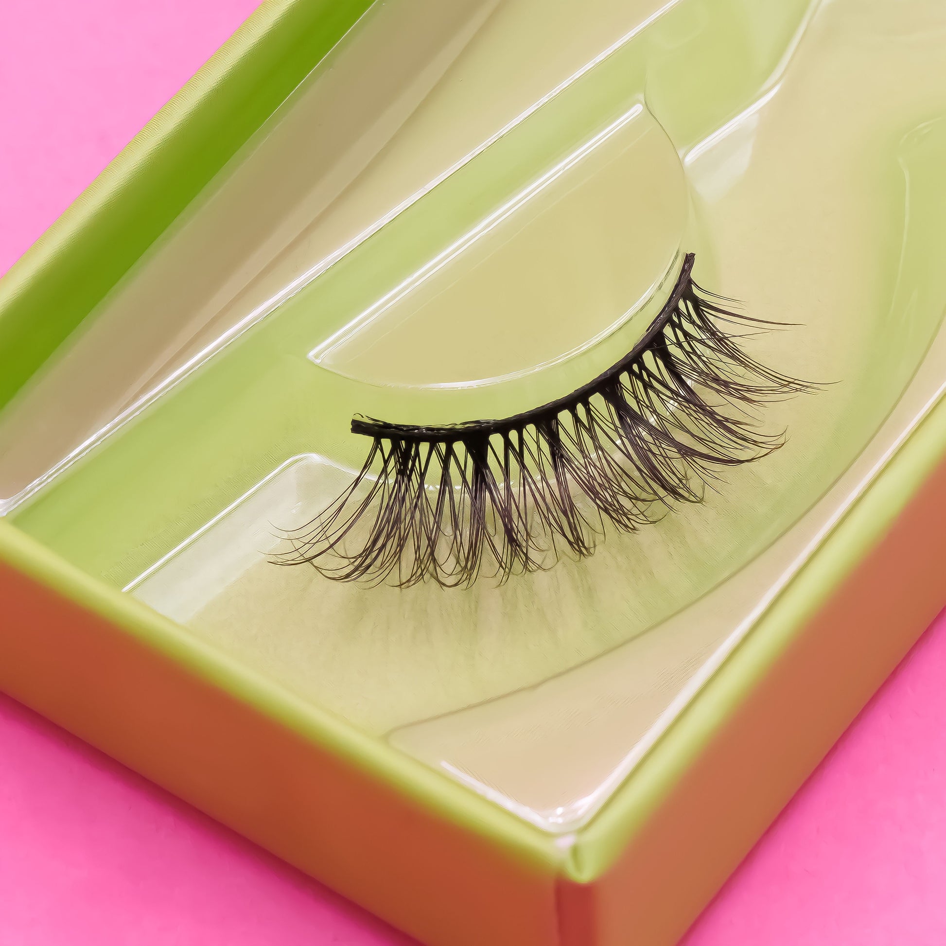 False eyelashes in a green and orange box on a pink background