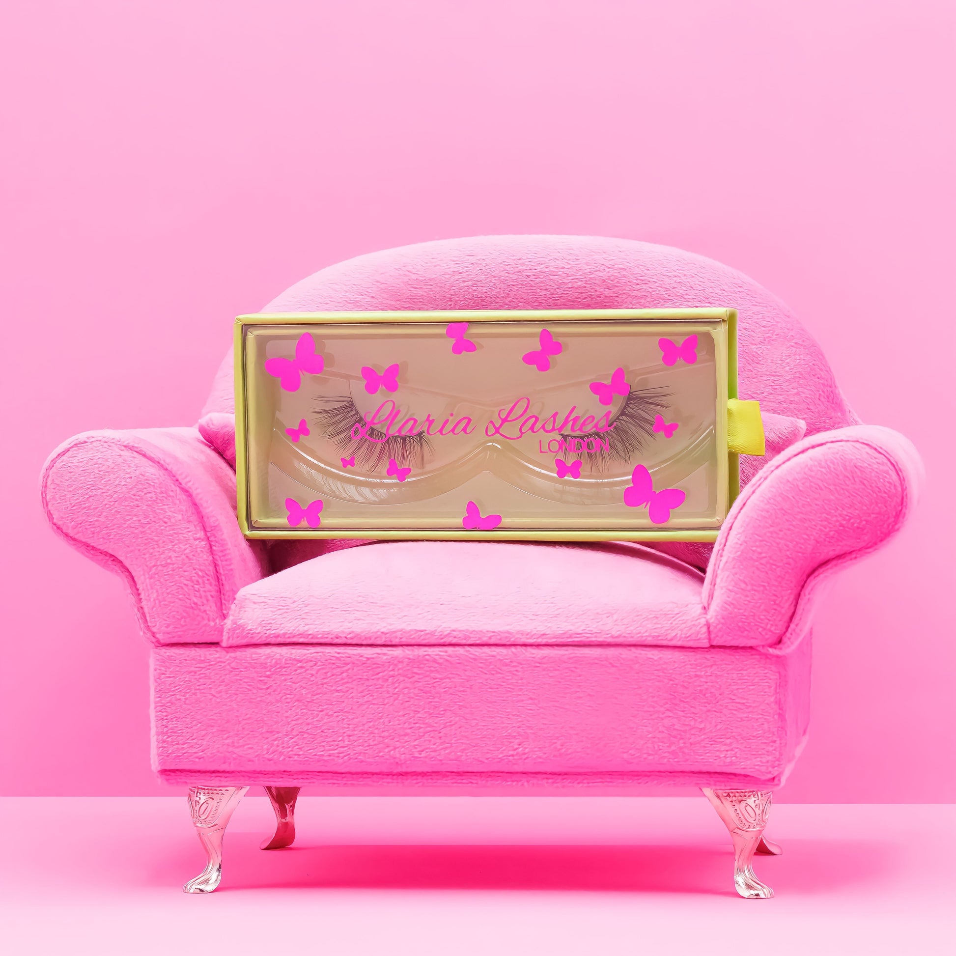 Pink armchair with a decorative box featuring false eyelashes and butterflies on a pink background