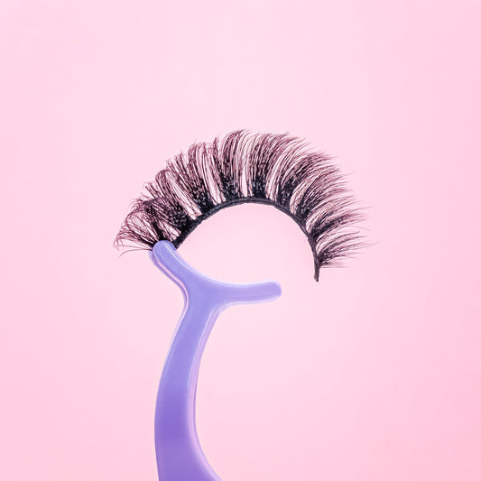False eyelashes on a blue holder against a pink background