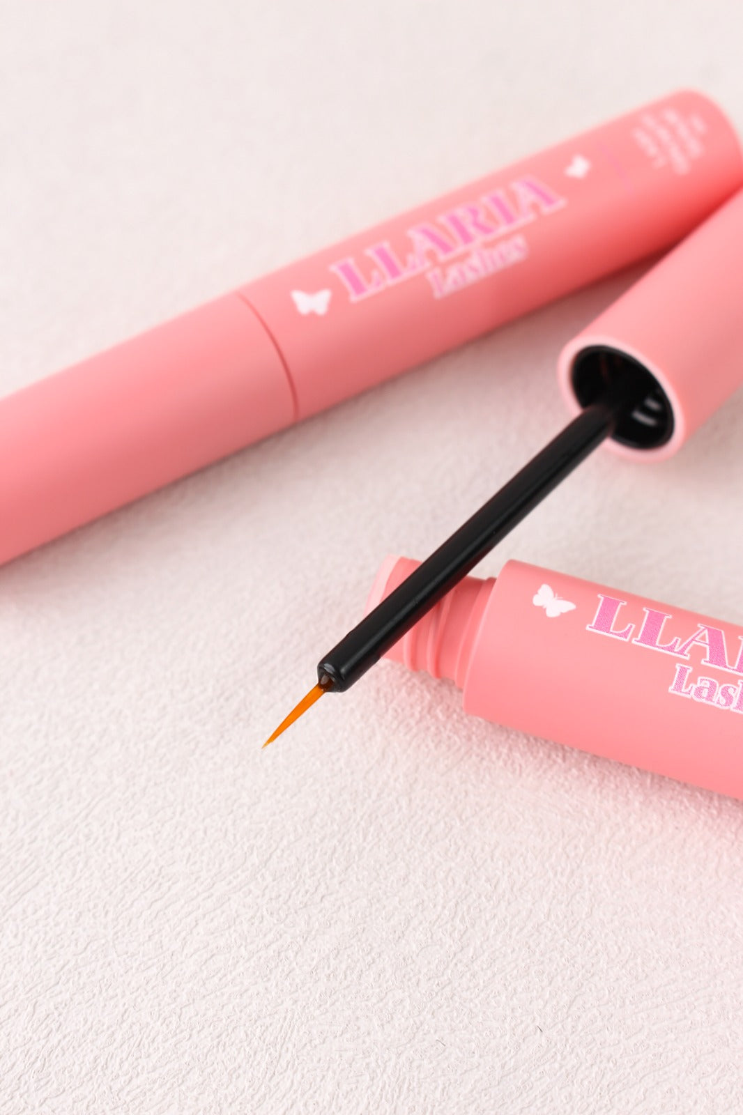 Pink eyelash extension product with applicator on a light background